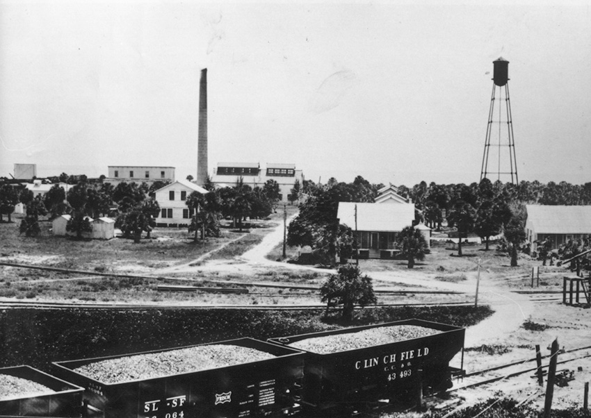 black and white photo of South Boca Grande - phosphate railroad cars on the foreground with water tower and buildings in the background