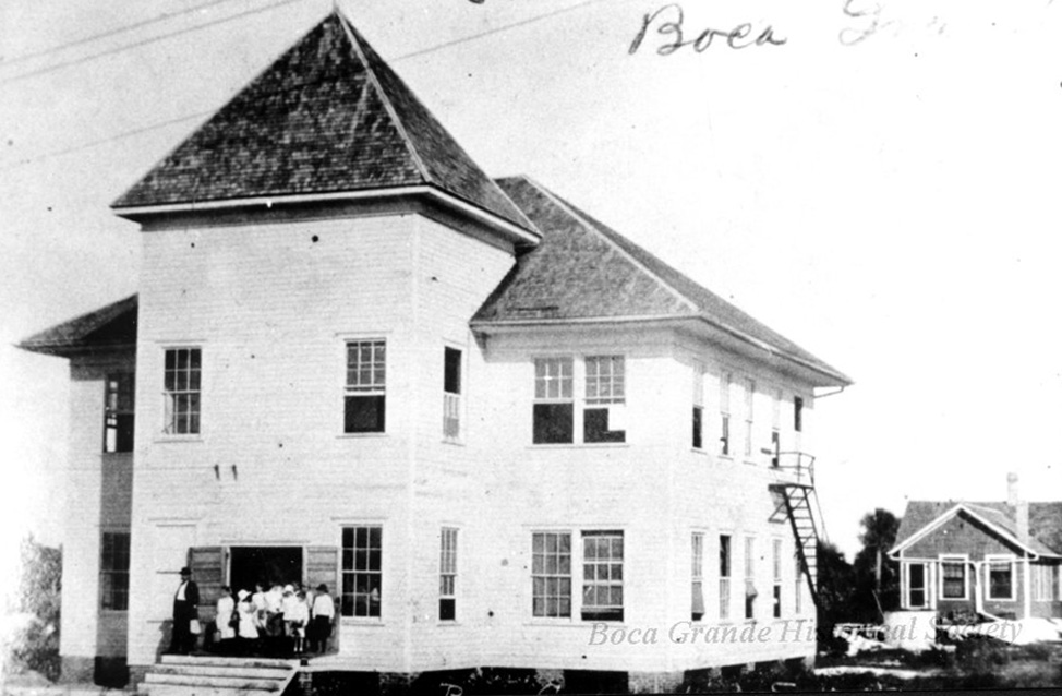 photo of an old two-story school building with students standing at the door